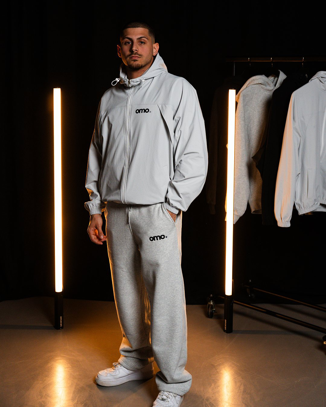 Model trägt omo Performance Windbreaker Grau und Essential Jogger Grau im Studio