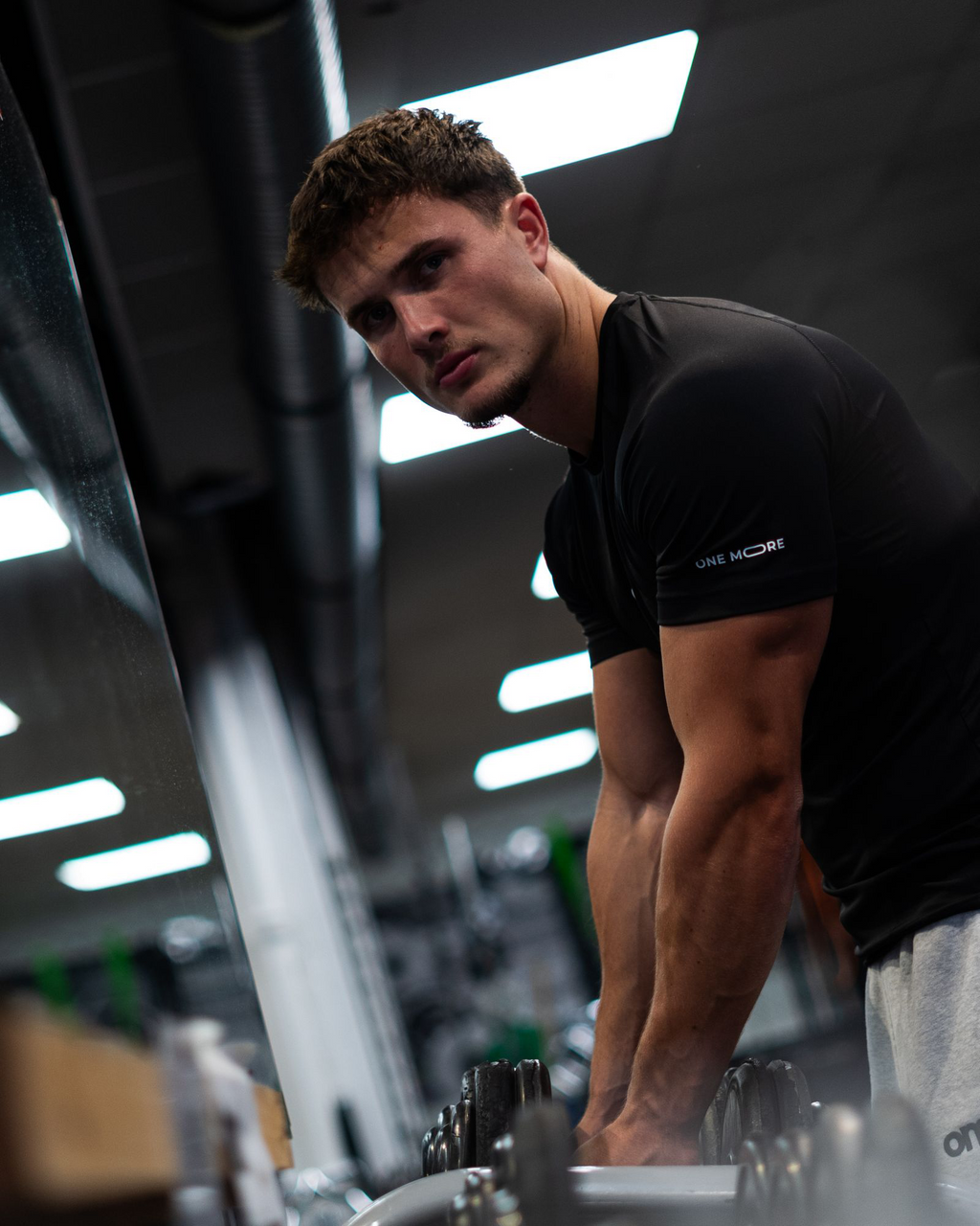 Model trägt omo Compression T-Shirt Schwarz und Essential Jogger Grau im Gym